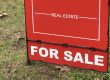 A Real Estate "FOR SALE" sign on a vacant lot for sale.