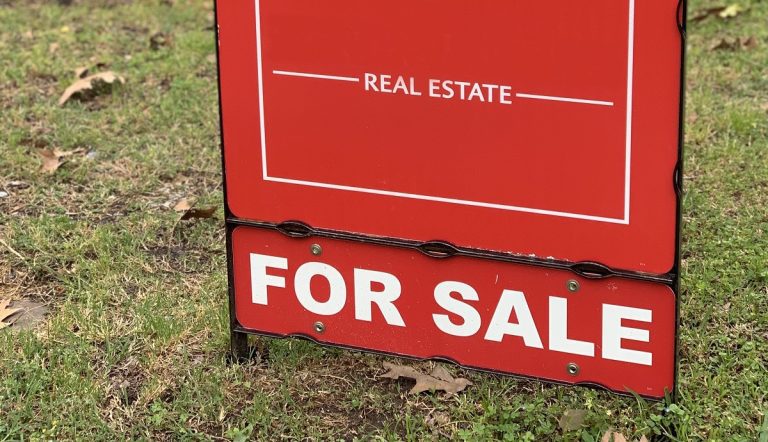 A Real Estate "FOR SALE" sign on a vacant lot for sale.